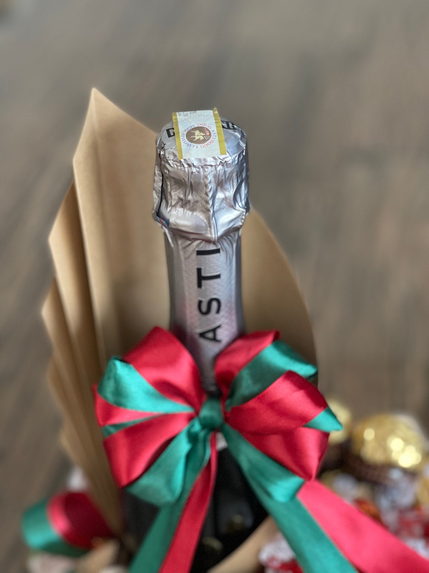 Wine and chocolate (ferrero, lindt and merci) arrangement. With Christmas ribbon for gift giving or as table centerpiece. Front close up photo with the bubbles Asti Martini. Mood and Scents.
