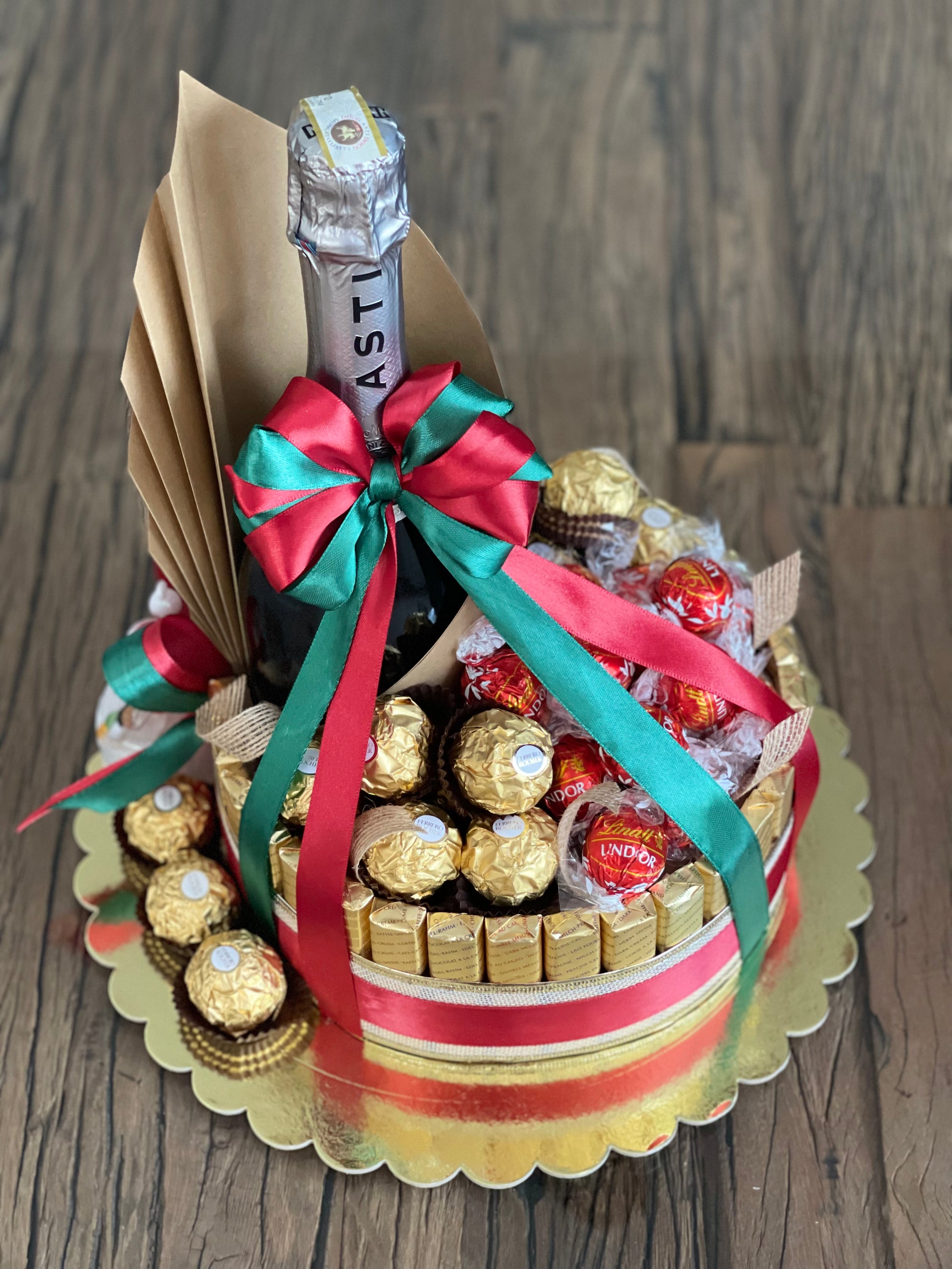Wine and chocolate (ferrero, lindt and merci) arrangement. With Christmas ribbon for gift giving or as table centerpiece. Front view photo. Mood and Scents!