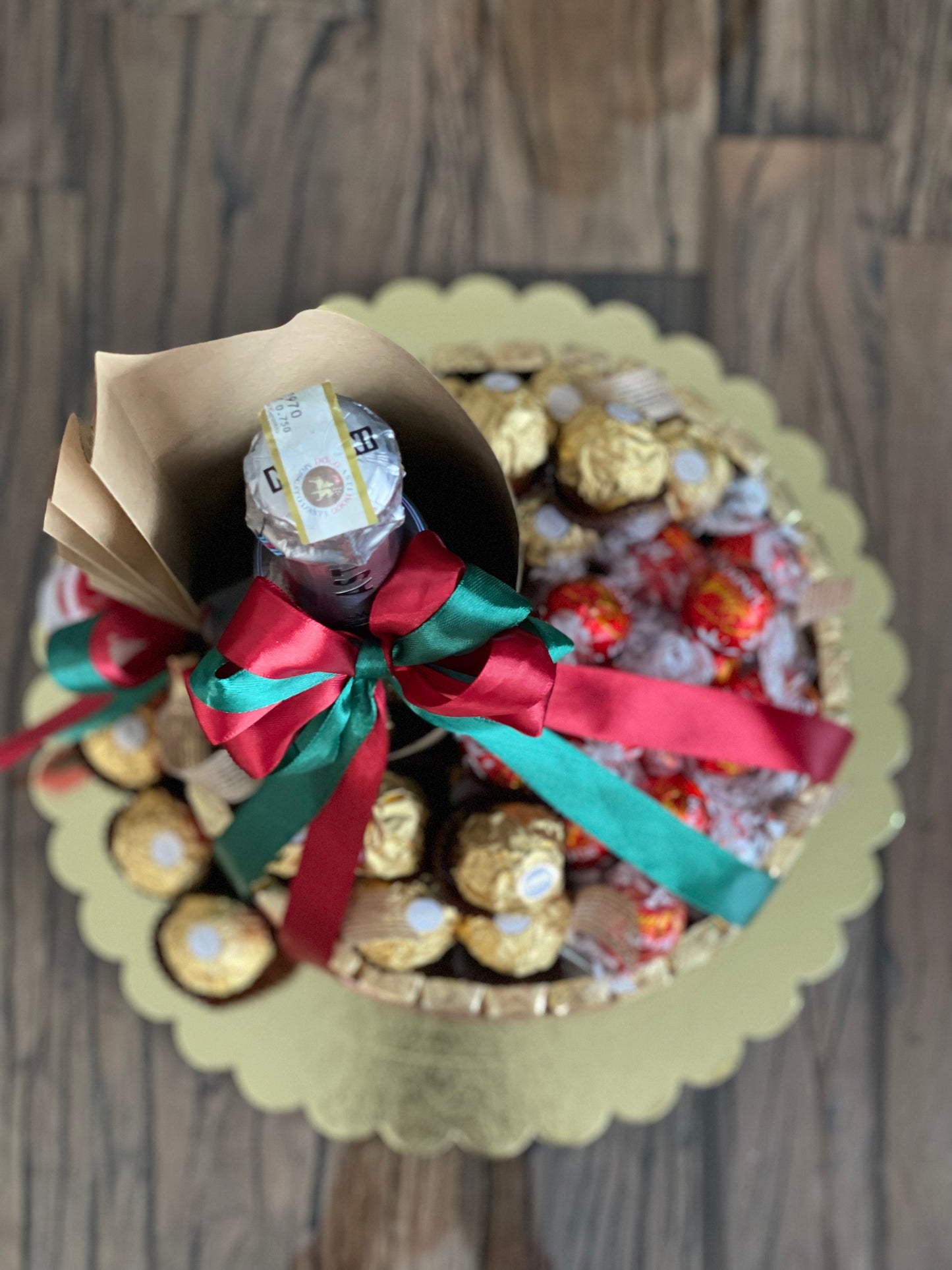 Wine and chocolate (ferrero, lindt and merci) arrangement. With Christmas ribbon for gift giving or as table centerpiece. Top view photo. Mood and Scents