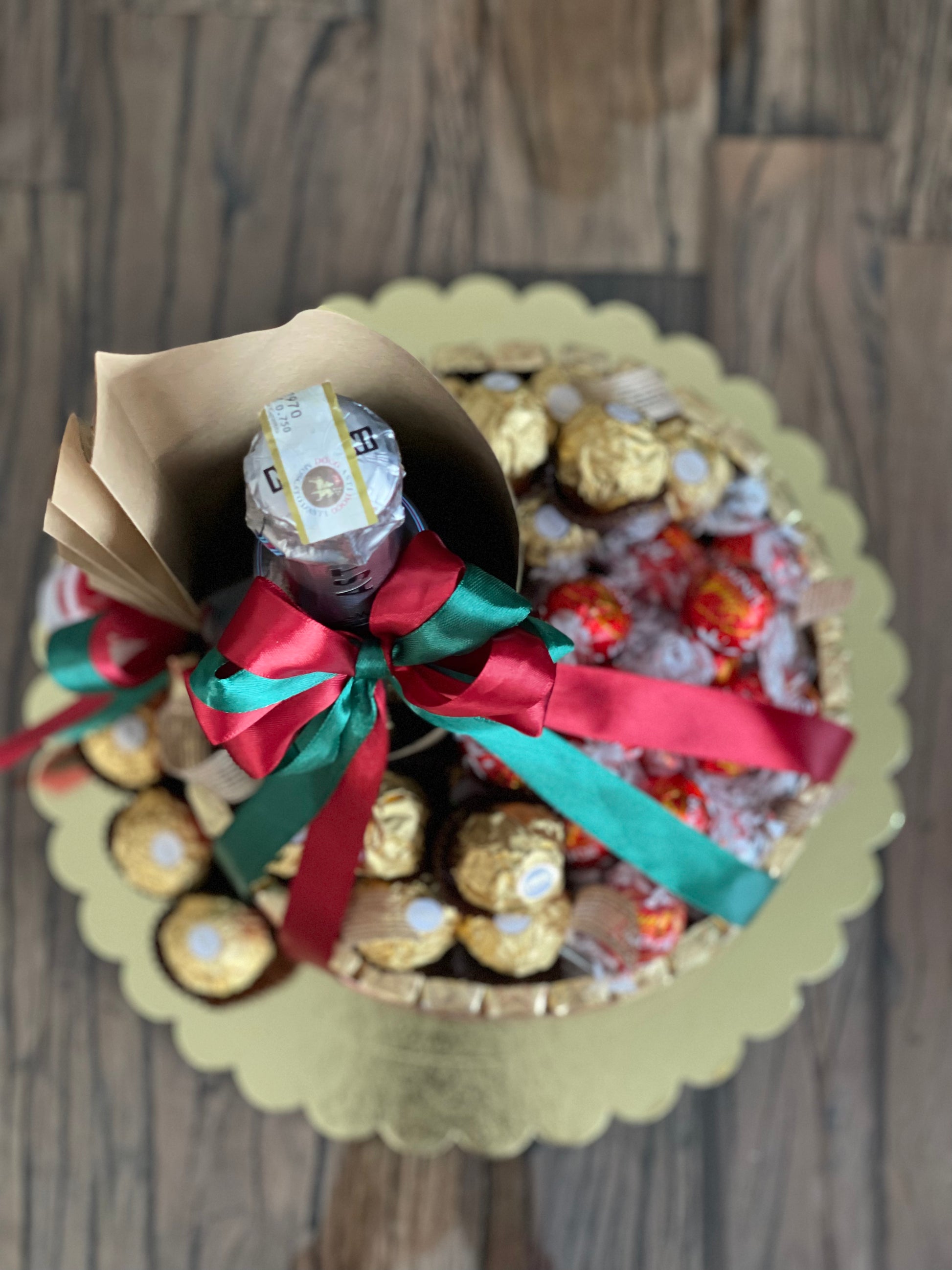 Wine and chocolate (ferrero, lindt and merci) arrangement. With Christmas ribbon for gift giving or as table centerpiece. Top view photo. Mood and Scents