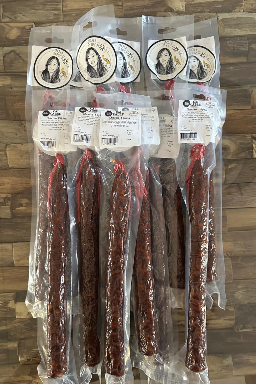 Packaged chorizo filipino sausages with brand stickers pinay sa barcelona on a wooden surface.
